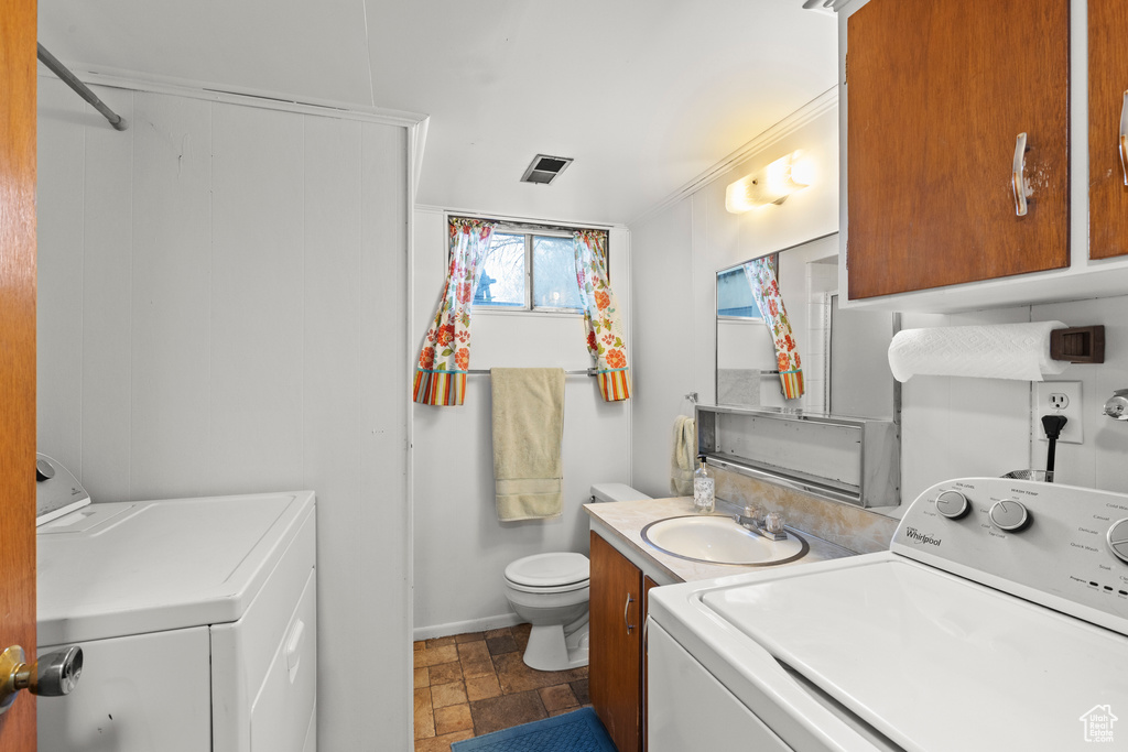Washroom featuring washer and dryer, laundry area, a sink, stone finish flooring, and visible vents