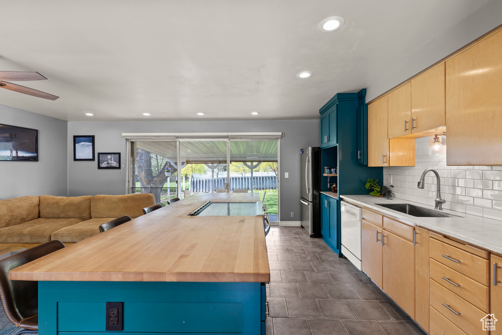 Kitchen featuring ceiling fan, white dishwasher, a sink, freestanding refrigerator, and recessed lighting