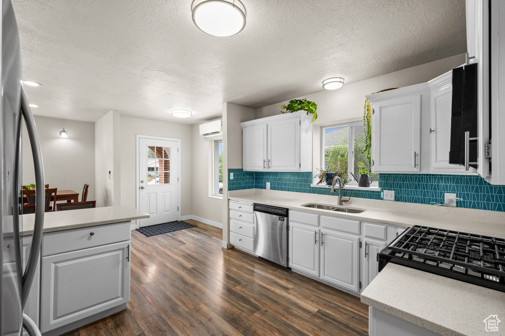 Kitchen featuring a wall mounted AC, a textured ceiling, stainless steel appliances, and a sink