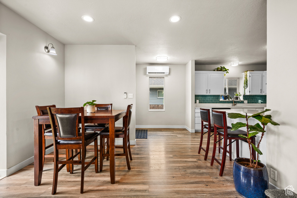 Dining room featuring recessed lighting, a wall mounted air conditioner, baseboards, and light wood-style flooring