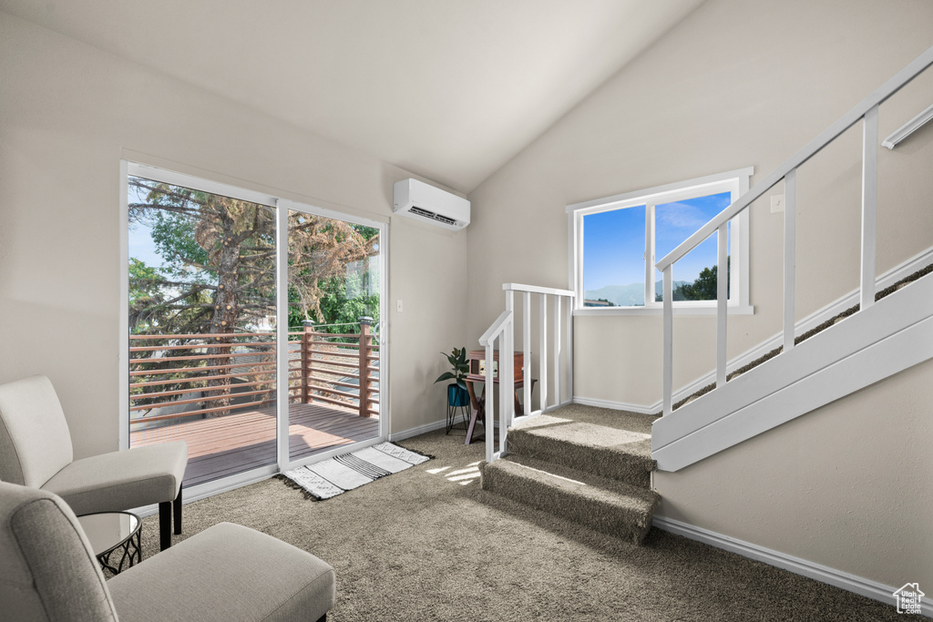 Carpeted living area featuring plenty of natural light, baseboards, lofted ceiling, and a wall unit AC
