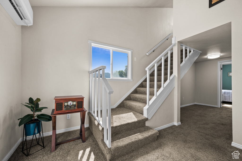 Staircase featuring baseboards, carpet flooring, and a wall unit AC