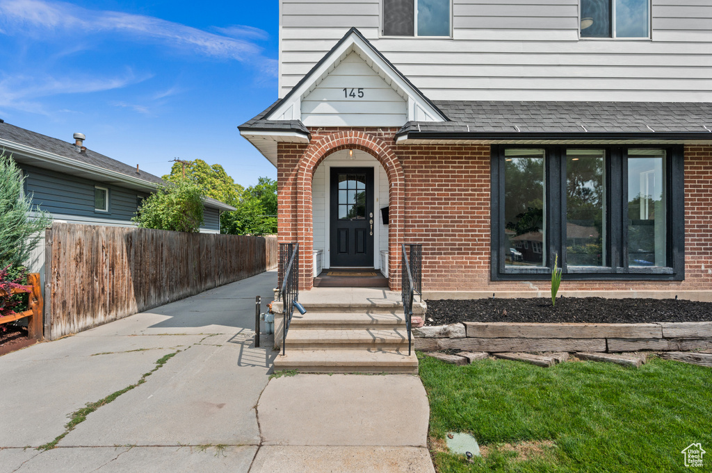 Doorway to property featuring brick siding and fence