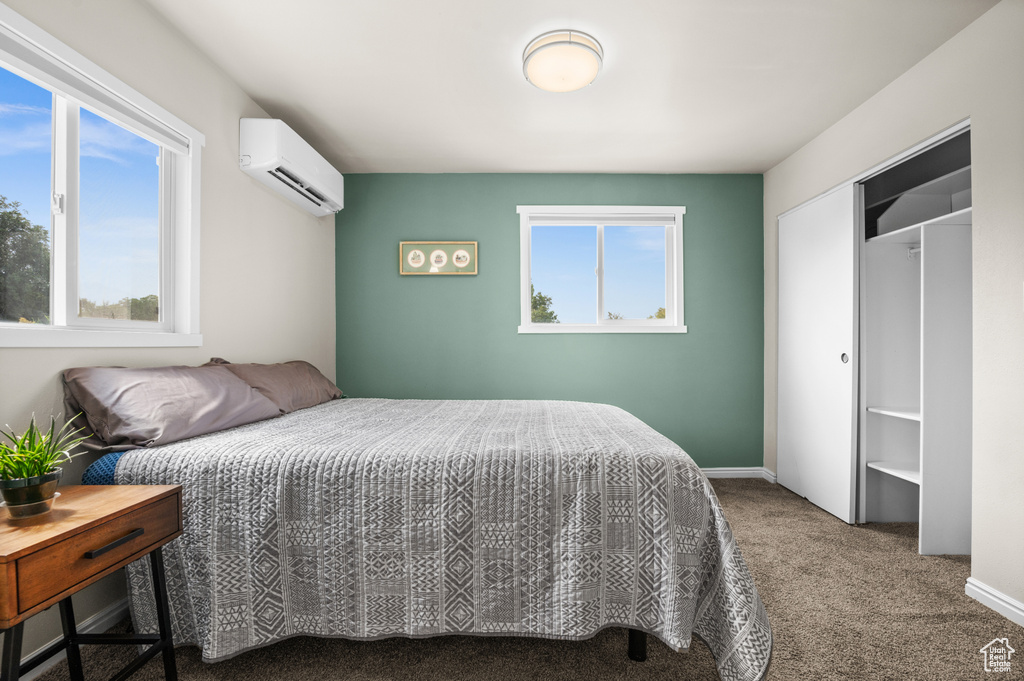Bedroom with carpet flooring, a wall unit AC, and multiple windows