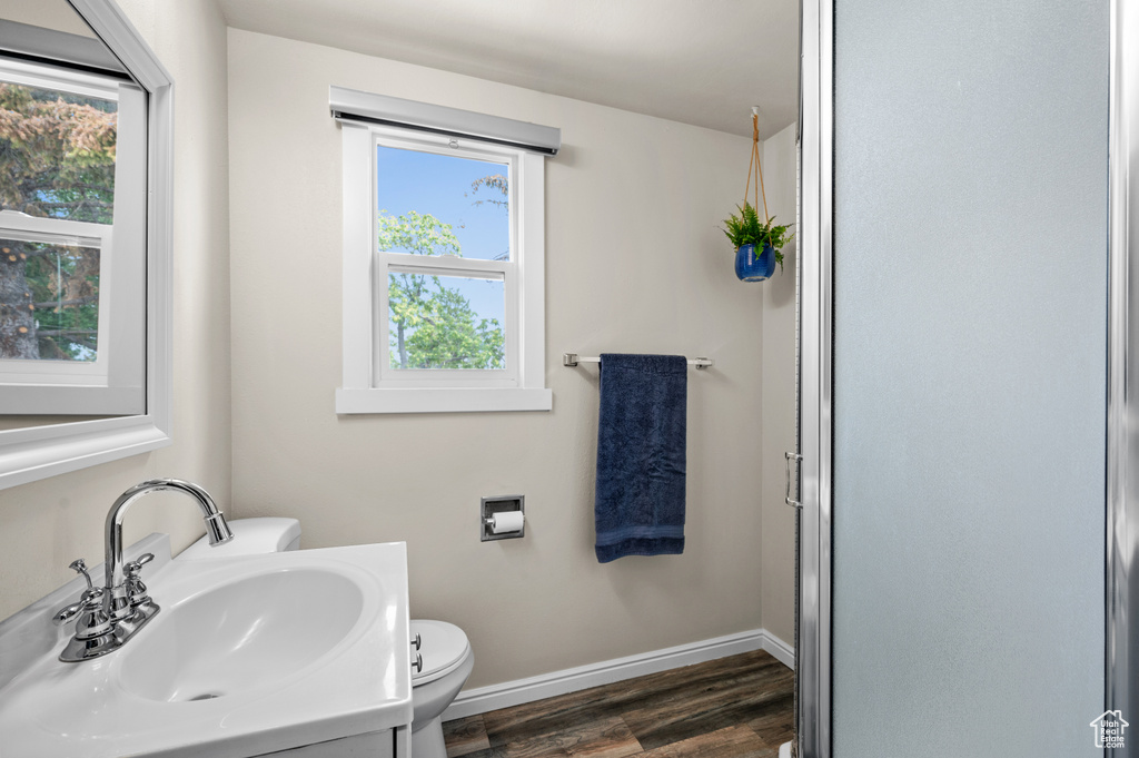 Bathroom featuring wood finished floors, a wealth of natural light, toilet, and baseboards