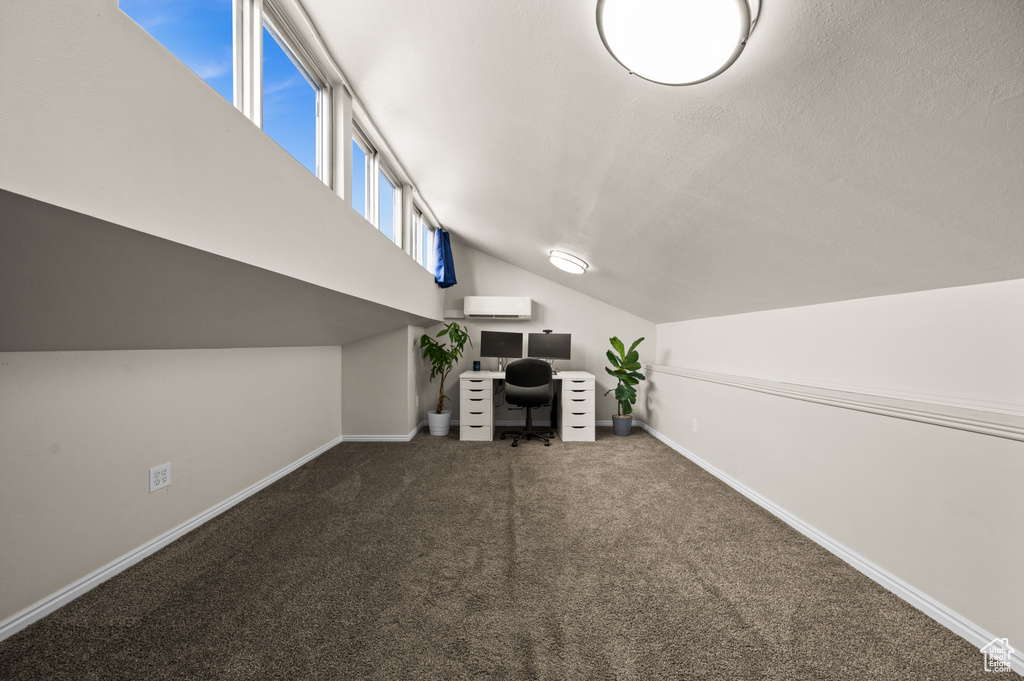 Interior space featuring lofted ceiling, baseboards, an AC wall unit, and carpet