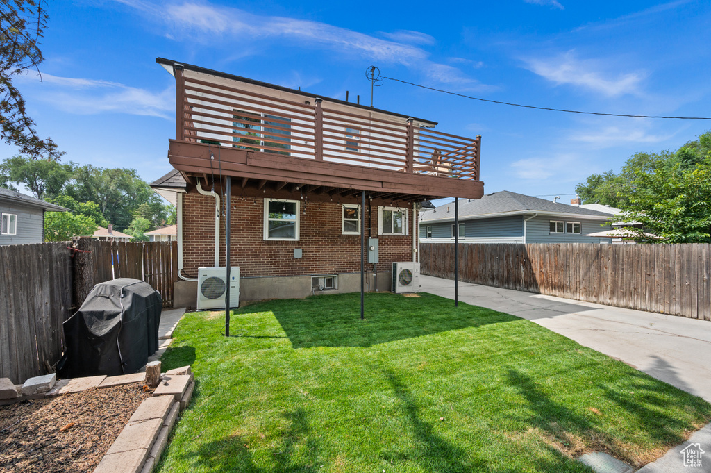 Back of house with ac unit, a fenced backyard, brick siding, and a yard