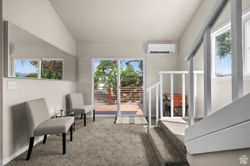 Sitting room with carpet floors, lofted ceiling, a wall unit AC, and plenty of natural light