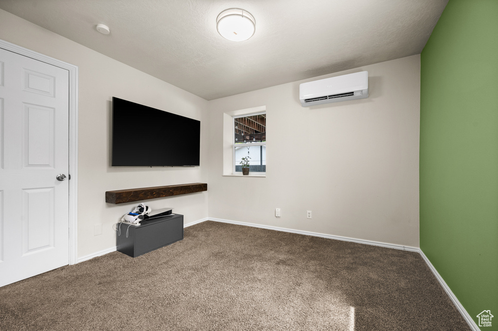 Unfurnished living room featuring a wall mounted air conditioner, carpet floors, and baseboards