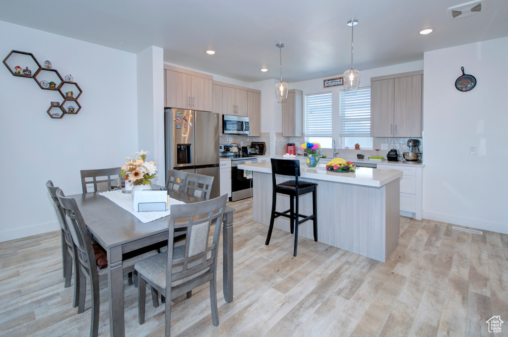 Dining space with light wood finished floors, visible vents, and recessed lighting