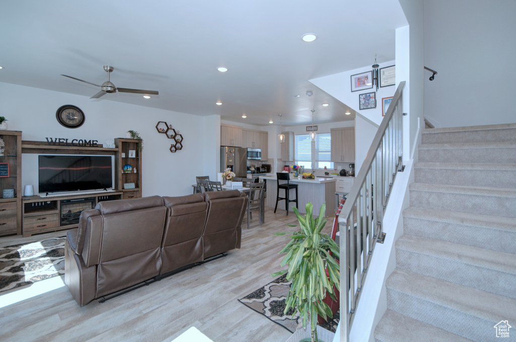 Living room with stairway, recessed lighting, a ceiling fan, and light wood-style flooring