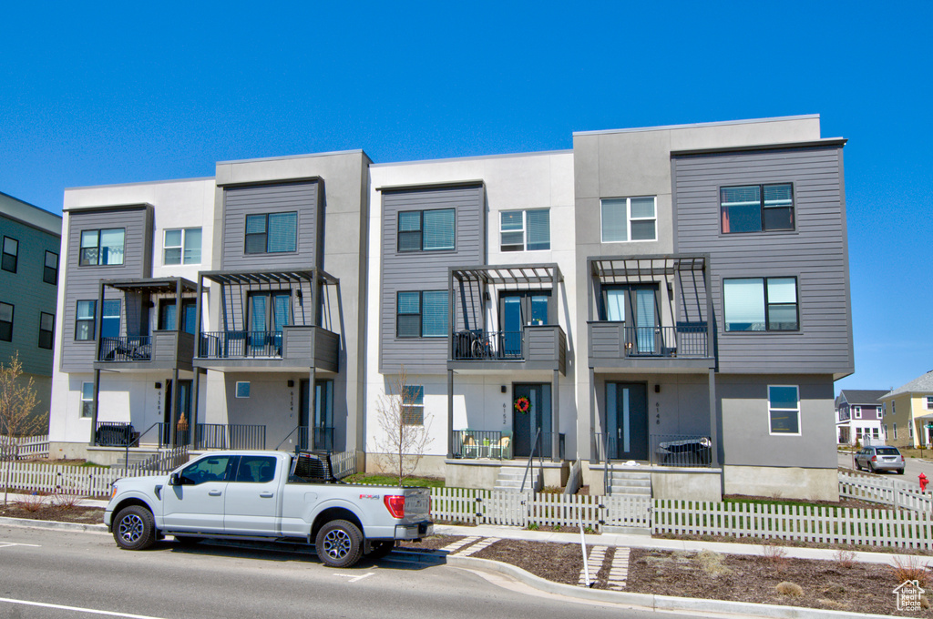 Multi unit property featuring stucco siding, a balcony, and fence private yard