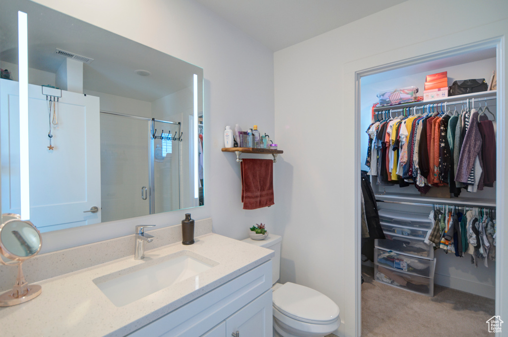 Full bath featuring toilet, a stall shower, visible vents, vanity, and a walk in closet