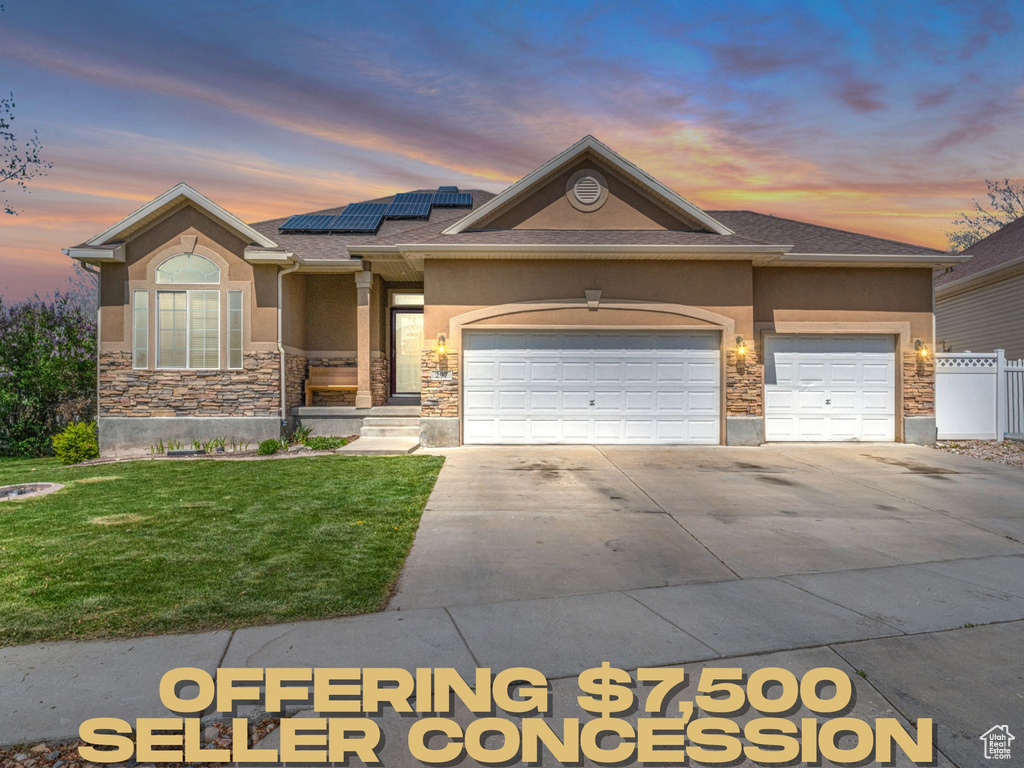 Single story home with stucco siding, solar panels, an attached garage, and driveway