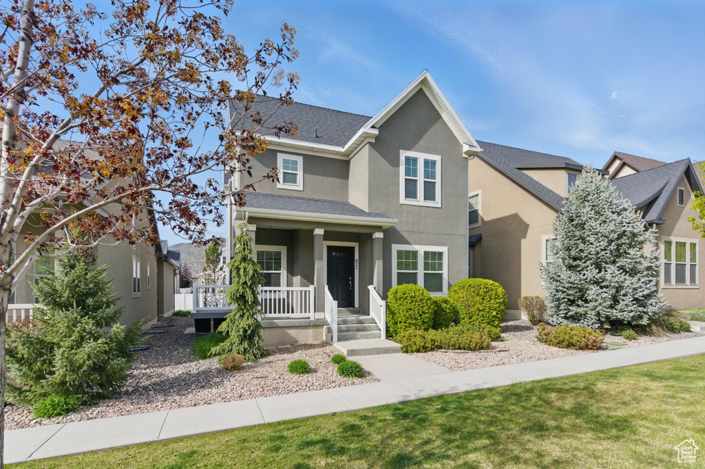 Traditional home with a shingled roof, covered porch, and stucco siding