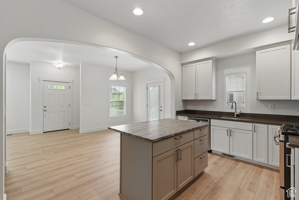 Kitchen featuring light wood finished floors, arched walkways, a sink, and stainless steel appliances