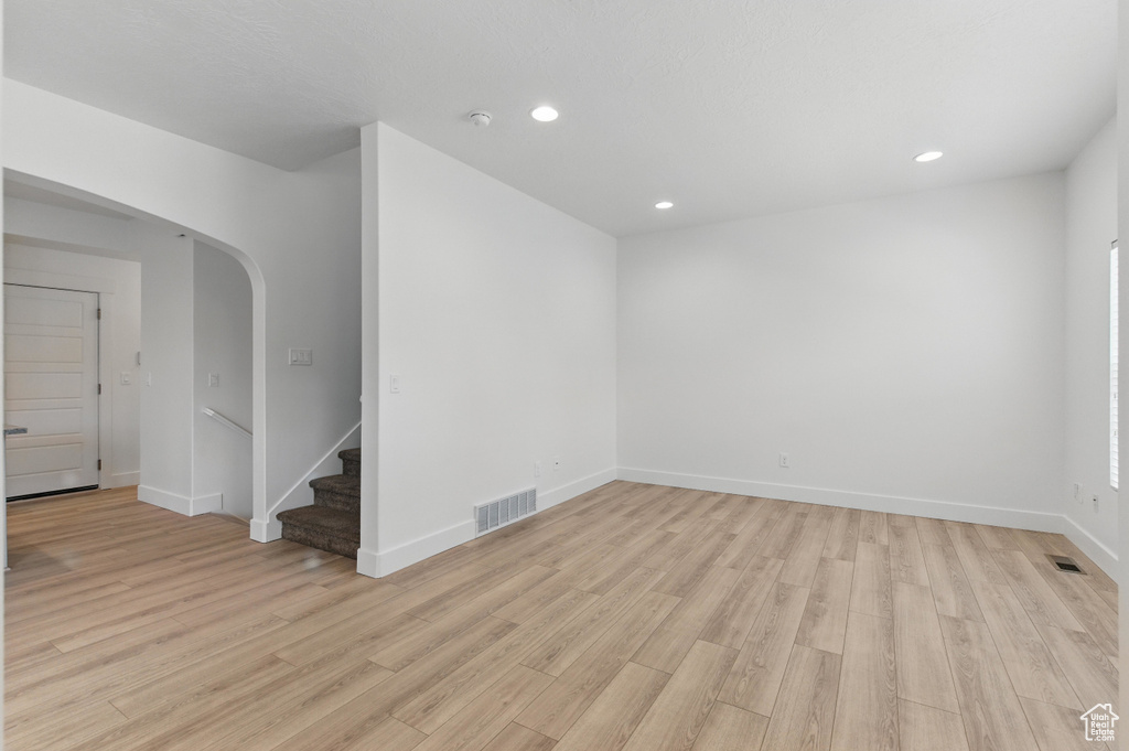 Interior space with arched walkways, visible vents, and light wood-type flooring