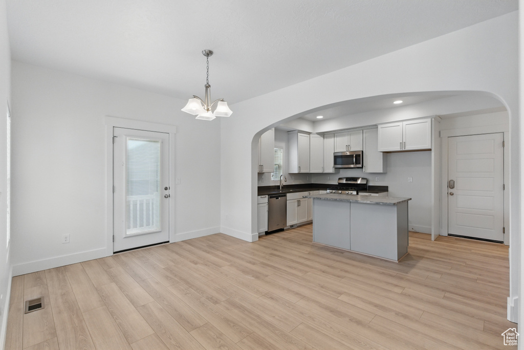 Kitchen with visible vents, a sink, arched walkways, light wood-style floors, and appliances with stainless steel finishes