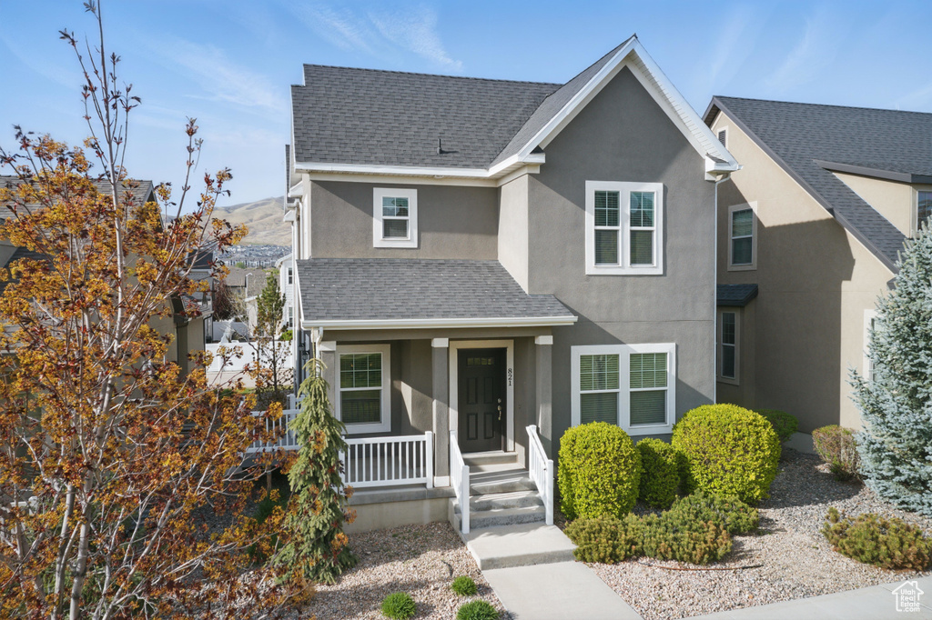 Traditional home featuring a porch, a shingled roof, a mountain view, and stucco siding