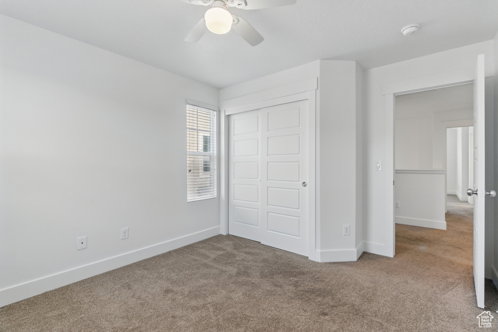 Unfurnished bedroom featuring a ceiling fan, baseboards, a closet, and carpet