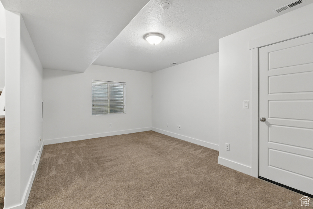 Spare room featuring carpet floors, a textured ceiling, visible vents, and baseboards