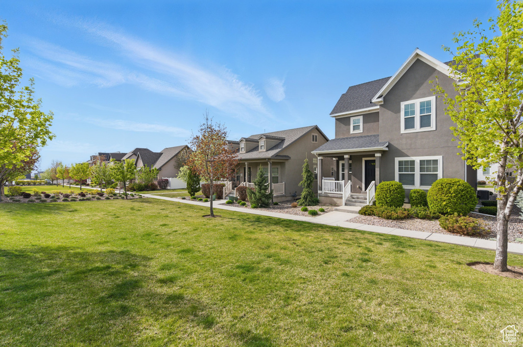 Traditional-style home with covered porch, a front yard, a residential view, and stucco siding