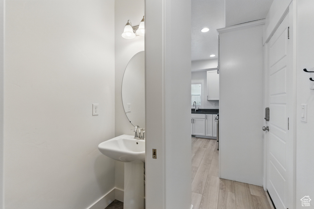 Bathroom with baseboards, wood finished floors, recessed lighting, and a sink