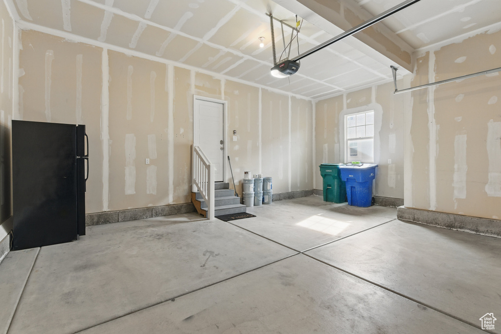 Garage featuring freestanding refrigerator and a garage door opener