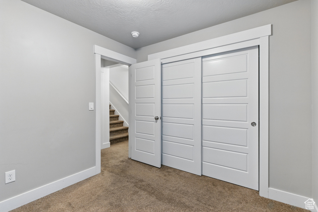 Unfurnished bedroom with baseboards, carpet floors, and a closet