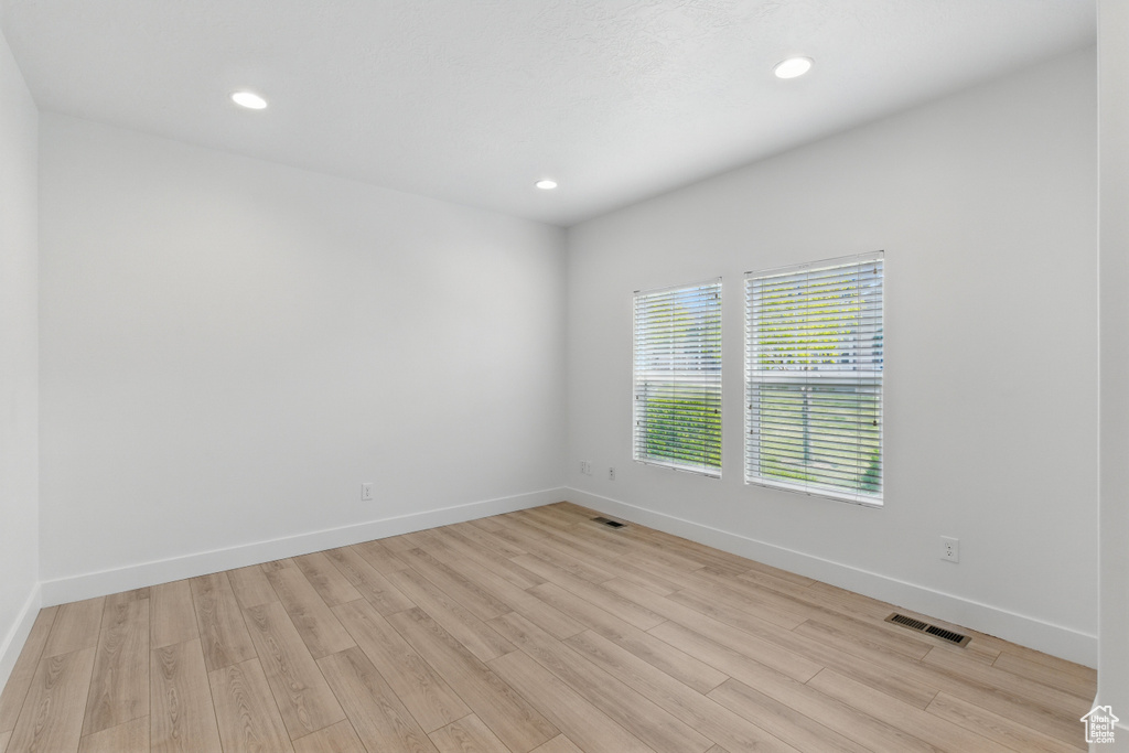 Unfurnished room with light wood finished floors, baseboards, visible vents, and recessed lighting