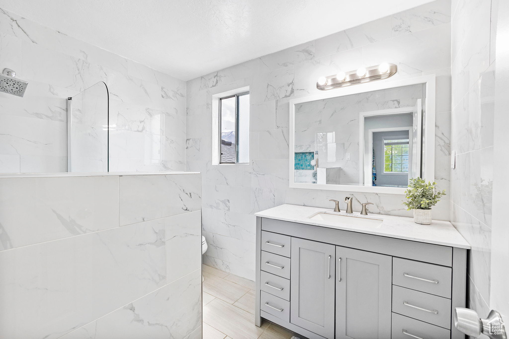 Bathroom featuring toilet, vanity, and tile walls