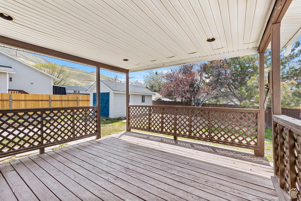 Wooden deck featuring a fenced backyard, an outbuilding, and a storage unit