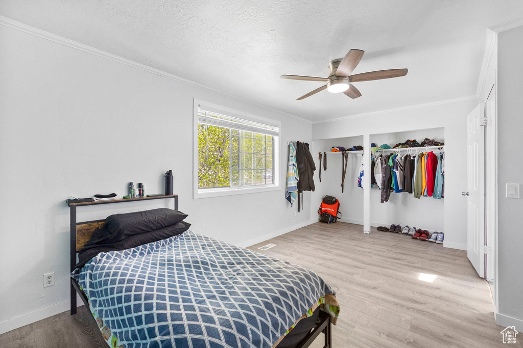 Bedroom with wood finished floors, crown molding, and baseboards