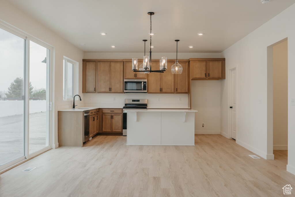 Kitchen featuring brown cabinets, plenty of natural light, appliances with stainless steel finishes, and a sink