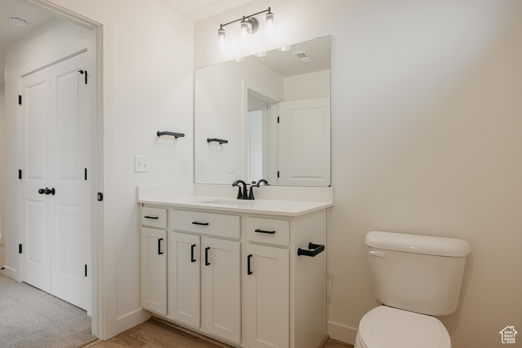 Half bathroom featuring visible vents, toilet, baseboards, and vanity