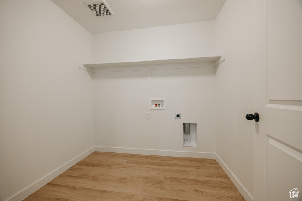 Washroom featuring hookup for a washing machine, hookup for an electric dryer, laundry area, light wood-style flooring, and visible vents