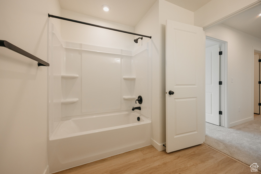 Bathroom with wood finished floors, baseboards, and shower / washtub combination