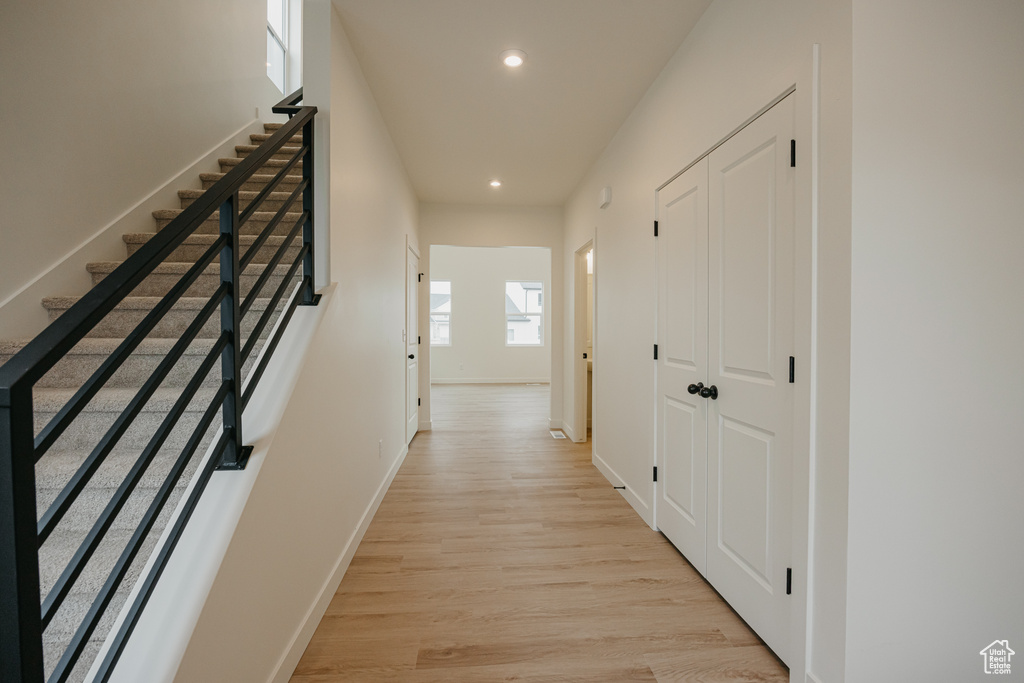Hall with recessed lighting, stairs, light wood finished floors, and baseboards