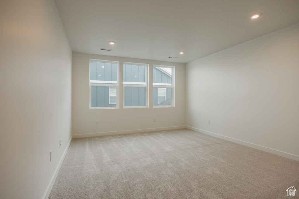 Empty room featuring baseboards, light carpet, visible vents, and recessed lighting