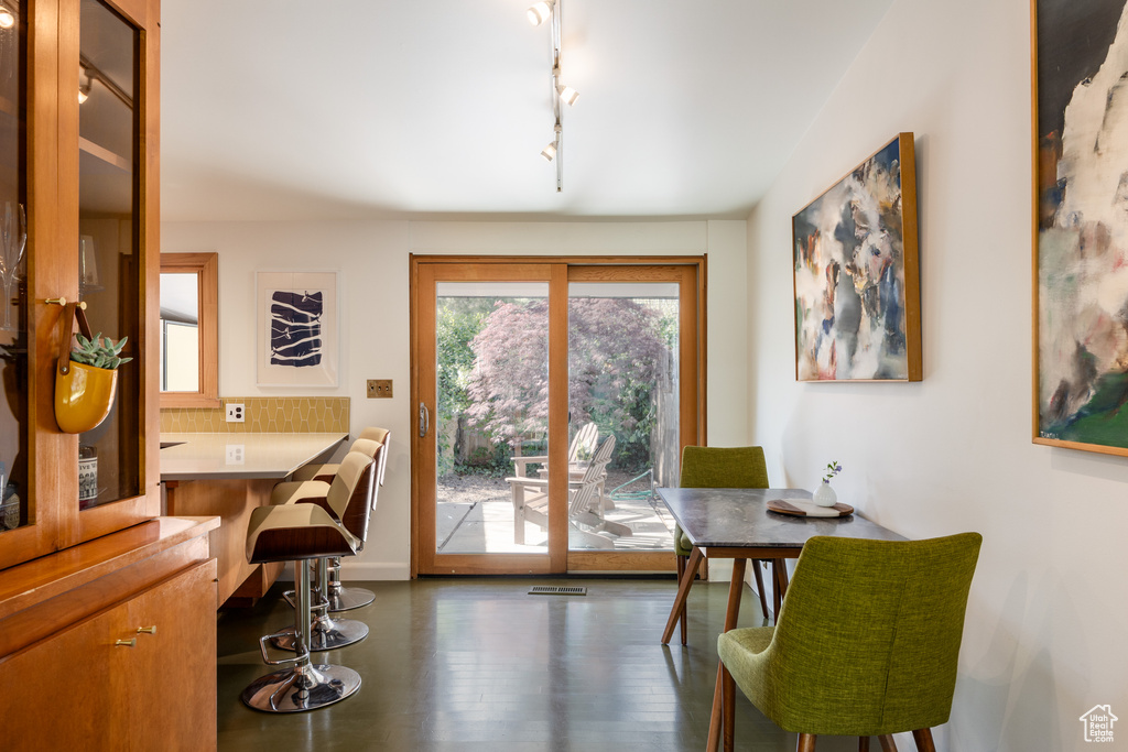 Dining area featuring rail lighting, baseboards, wood finished floors, and visible vents