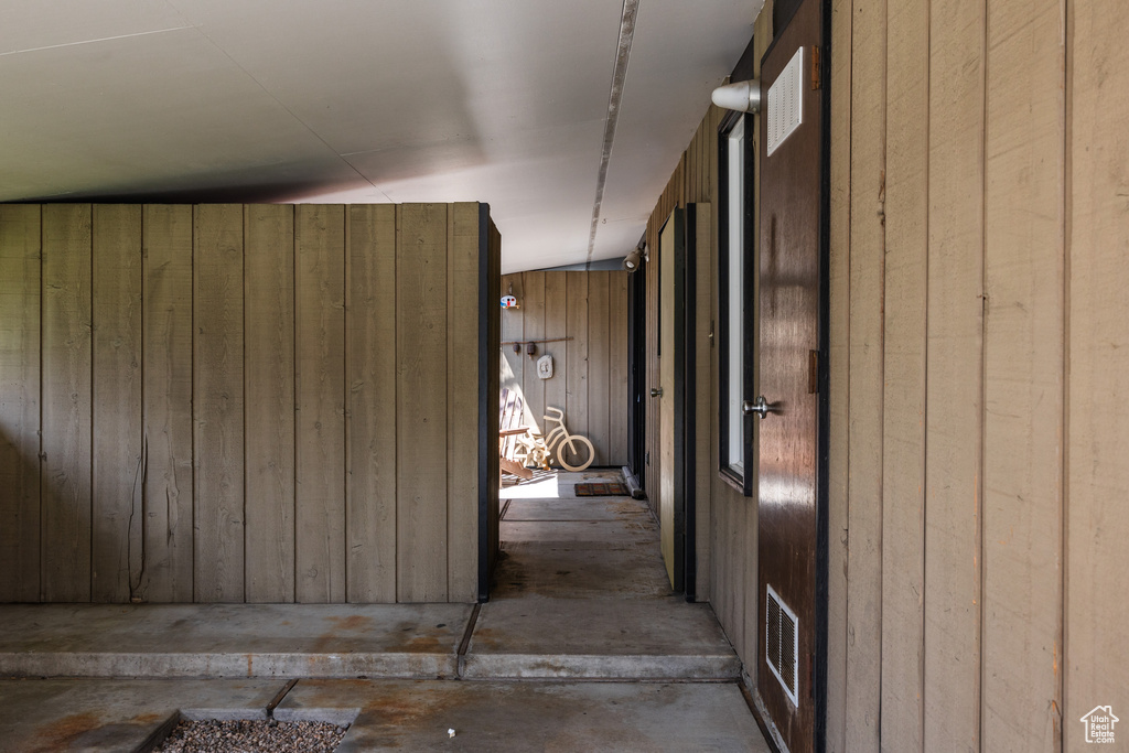 Corridor featuring visible vents, wood walls, and concrete flooring