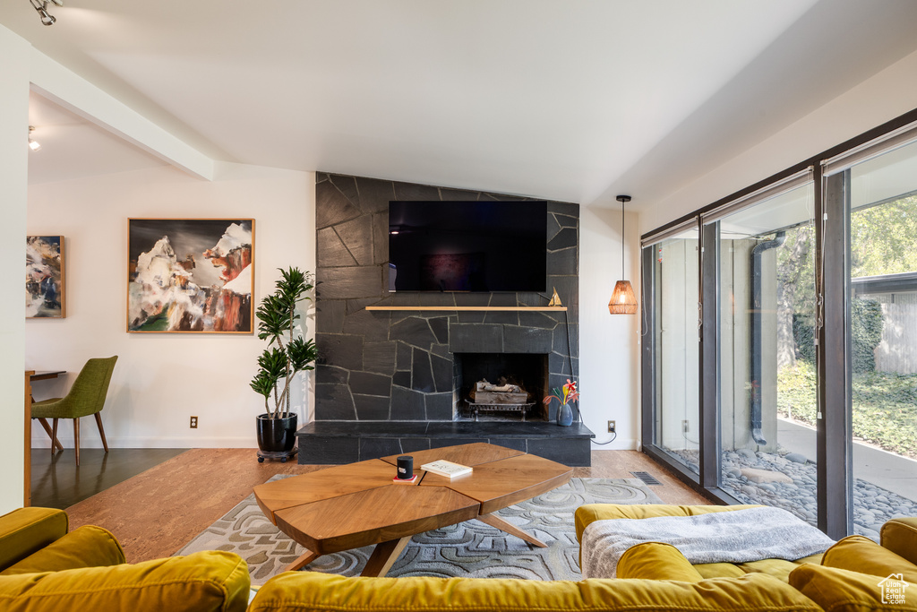 Living area featuring lofted ceiling with beams, a tile fireplace, baseboards, and light wood-style floors