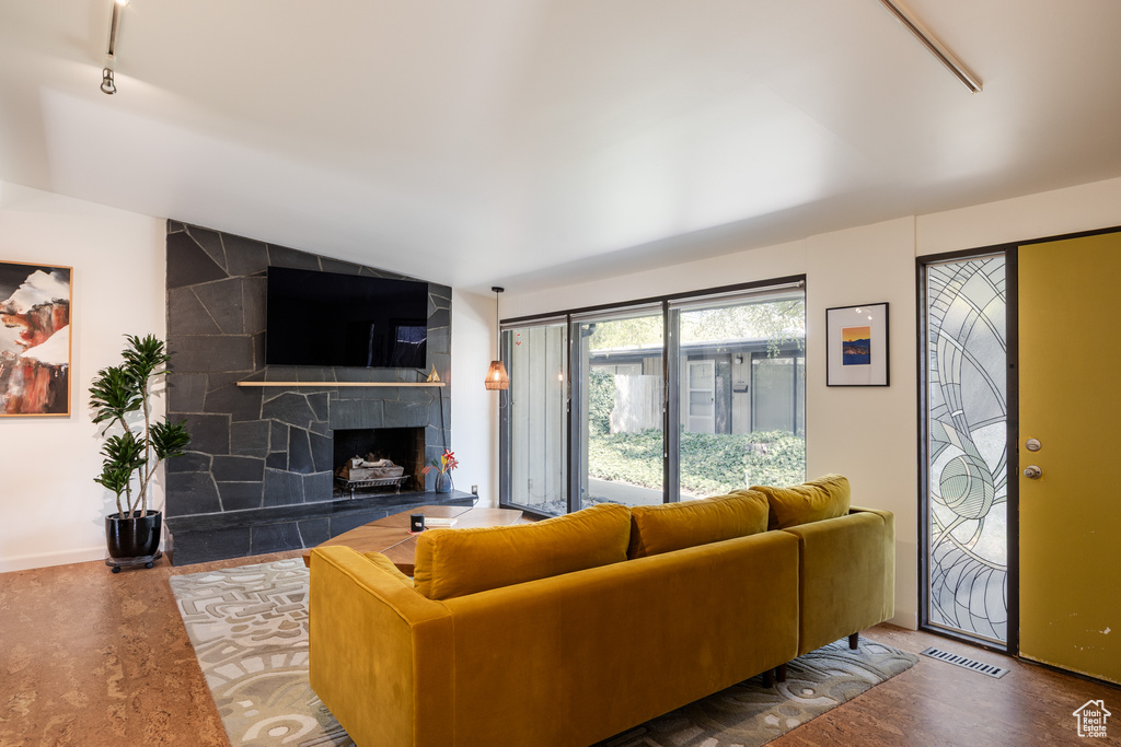 Living room with a tiled fireplace, visible vents, baseboards, lofted ceiling, and track lighting