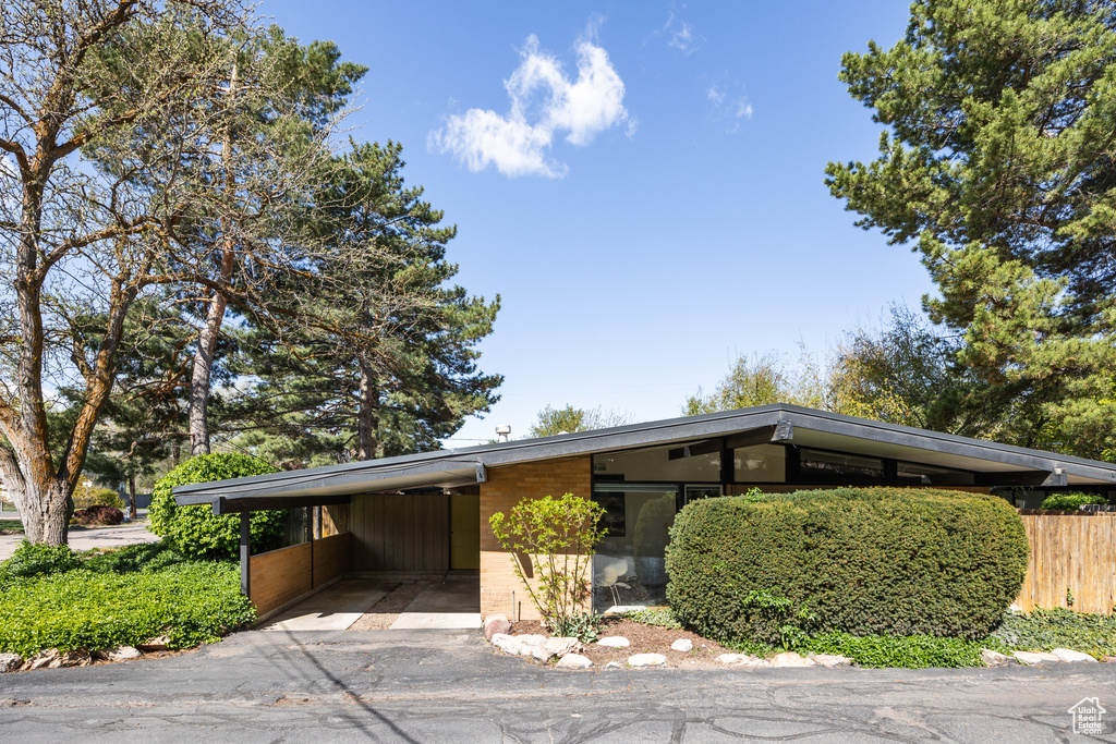 View of car parking with a carport, driveway, and fence