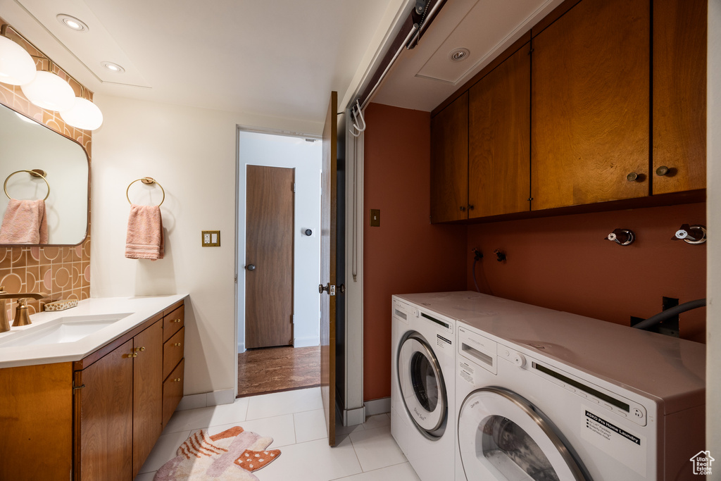 Washroom featuring light tile patterned floors, baseboards, a sink, and independent washer and dryer
