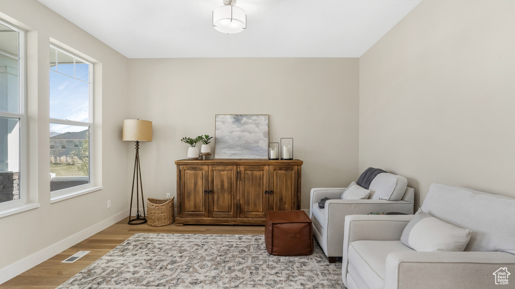 Sitting room with light wood-type flooring, visible vents, and baseboards
