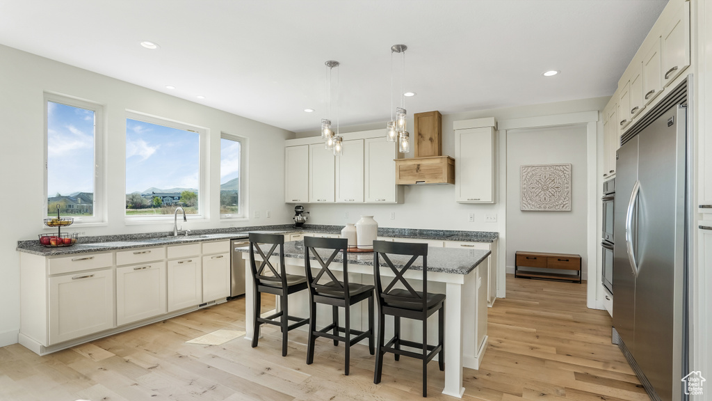 Kitchen with a center island, a sink, a breakfast bar area, light wood-type flooring, and stainless steel appliances