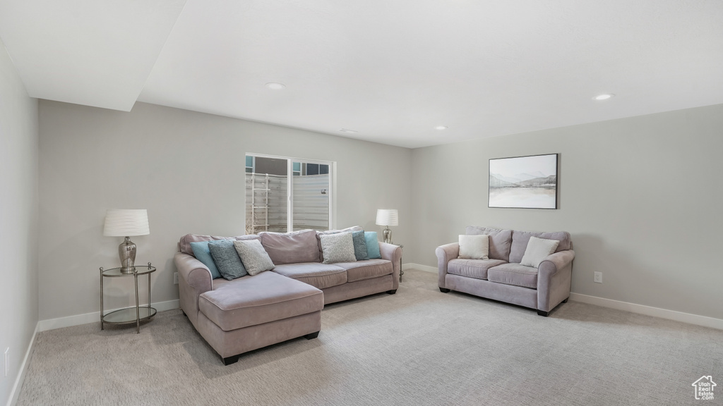 Living area with light colored carpet, baseboards, and recessed lighting
