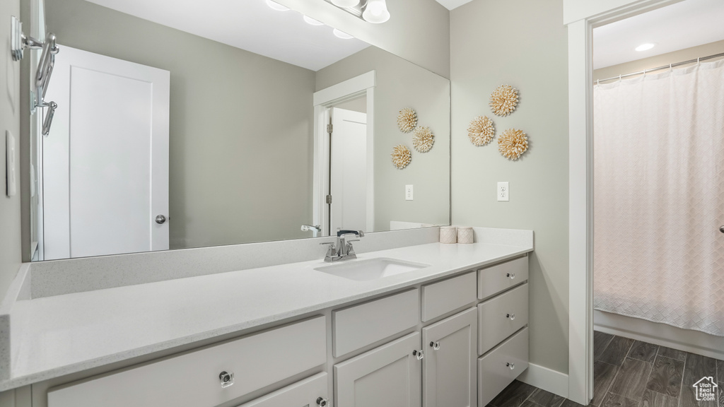 Bathroom with a shower with curtain, baseboards, wood finished floors, and vanity