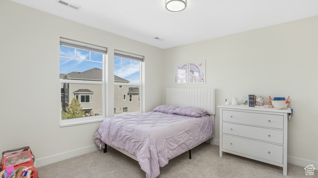 Bedroom with light carpet, visible vents, and baseboards